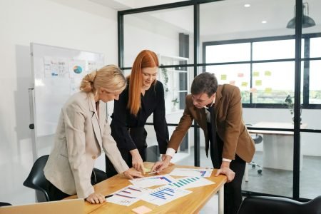 Three young business professionals standing together and discussing over business report